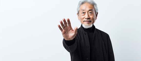 Elderly Asian man with grey hair on white backdrop offering copy space image