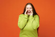 © ViDi Studio - Young ginger chubby plus size woman wears green sweatshirt casual clothes scream shout about sales discount, hands near mouth isolated on red orange background studio. Lifestyle body positive concept.