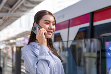 Wall Mural - Asian woman talk on phone while waiting train at platform of metro station. 