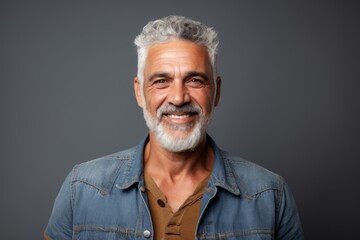 Wall Mural - Portrait of a smiling man in his 70s wearing a rugged jean vest isolated on minimalist or empty room background