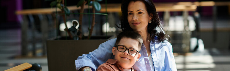 A mother and her son with Down syndrome are seen walking together in a shopping mall, enjoying each others company.