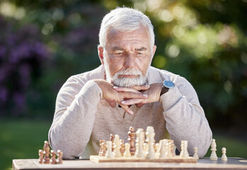 Thinking, retired man and playing chess in garden for challenge and strategy in nature. Elderly male person, planning and board game in countryside with intelligence and focus at table in park