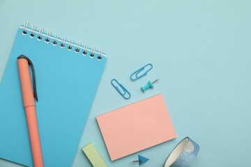 Wall Mural - Flat lay composition with notebook and different stationery on light blue background, space for text