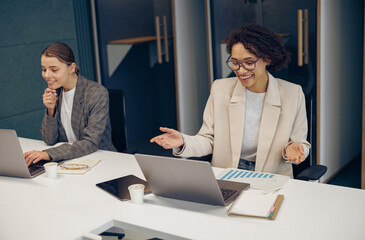 Wall Mural - Smiling businesswoman talking with client via video call while sitting in coworking 