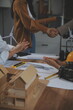 © Sirikarn Rinruesee - Construction team shake hands greeting start new project plan behind yellow helmet on desk in office center to consults about their building project. in sun light