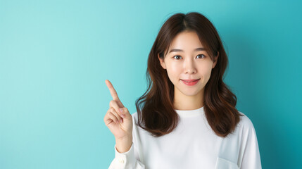 A young and attractive Asian woman, confidently presenting with a pointing gesture, against a light blue background.