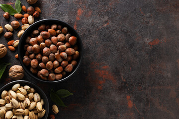 Wall Mural - Different types of nuts in black bowls on a dark background