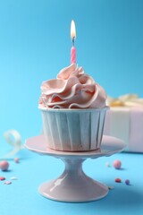 Wall Mural - Delicious birthday cupcake with burning candle and sprinkles on light blue background, closeup