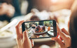 © NonVig/peopleimages.com - Hands, dinner and food by photography for blog on smartphone, plate of turkey and person vlogging. Table, cellphone and camera for social media post, meat and meal with culinary for review on web app