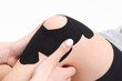 © MartaKlos - Kinesiology taping.Physical therapist applying kinesiology tape to patient knee.Therapist treating injured knee of young athlete.Post traumatic rehabilitation