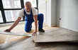 © anatoliy_gleb - Male construction worker laying laminate wooden planks on floor underlayment. Man in work overalls installing laminate wood flooring in new flat. Home renovation concept.