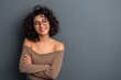 © Jani's Stocks - Portrait of a young latin woman with pleasant smile and crossed arms isolated on grey wall with copy space. Beautiful girl with folded arms looking at camera against grey wall. Cheerful hispanic woman