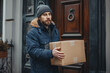 © ValNik Creations - Delivery service. Courier. A courier holds parcels on the threshold near the door, close-up. Parcel delivery