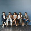 © Delmaine/peopleimages.com - Business people, technology and conversation in waiting room for interview, meeting or recruitment on chair. Hiring, HR and diversity candidates in office for opportunity, onboarding or employment