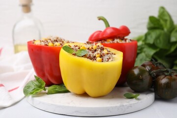 Wall Mural - Quinoa stuffed bell peppers, basil and tomatoes on white table, closeup