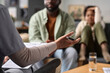 © Mediaphotos - Close up of female therapist gesturing and talking to father and son in family support session focus on hand holding pen copy space