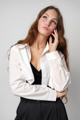 Wall Mural - Confident Young Woman With Long Wavy Hair Posing in Casual Attire Against a Gray Backdrop