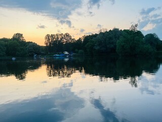 Wall Mural - Fantastic cloudy sky reflection on the lake surface, trees silhouettes reflection on the lake, evening twilights lake in the park