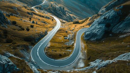 Wall Mural - A scenic aerial view of a winding road through mountains, perfect for depicting the freedom and adventure of a road trip