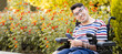 ©  Yistocking - A person with a disability sits in a wheelchair at an outdoor park at sunset.The adult man looks at the camera happily while holding a mobile phone.Disabled people in wheelchairs concept.