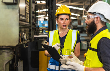 Wall Mural - Factory engineer man and woman working with heavy machinery in manufacturing factory