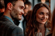 © Amparo Garcia - A man and a woman are smiling at each other in a crowded room, the man is wearing a suit and the woman is wearing a dress, they are both holding wine glasses