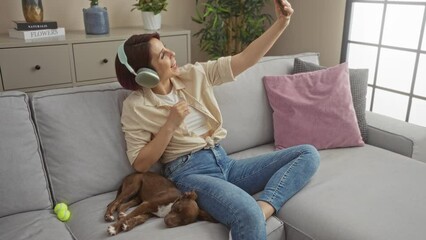 Poster - A young woman with headphones uses her phone to record a video in a living room, sitting comfortably on a couch with a sleeping dog.