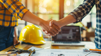 Poster - Close-up of a handshake at a construction site with tools and blueprints