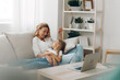 © SHOTPRIME STUDIO - Mother and daughter enjoying quality time on the couch with a laptop and bookshelf in the background