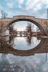 Aufkleber - A photograph of a bridge spanning a body of water with a cloudy sky overhead