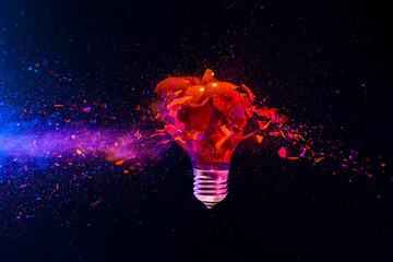 Wall Mural - Red light bulb exploding with colorful powder on dark background