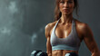 © Ayla - Portrait of a muscular woman lifts dumbbells with gray background, Building muscle and exercising to stay healthy and for a fit physique.