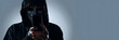 © john - Hacker Anonymous and face mask with smartphone in hand. Man in black hood shirt holding and using mobile phone on white background. Represent cyber crime data hacking or stealing personal data concept