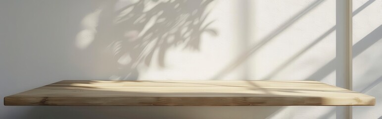 Empty light wood table top with sun rays and shadow on white wall background