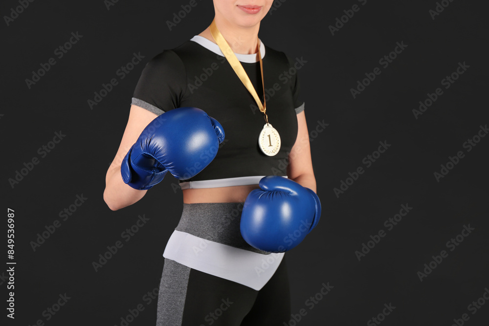 Female boxer with first place medal on black background