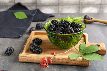 Canvas Print - Bowl and wooden board with fresh blackberries on grey table