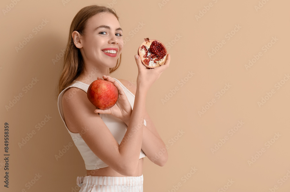 Young woman with pomegranate on beige background