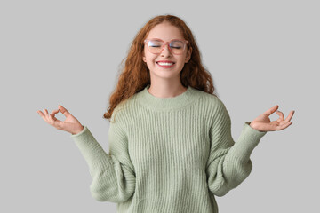 Wall Mural - Portrait of relaxed young woman meditating on grey background