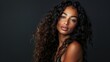 © MD Media - A beautiful woman with long curly hair posing for the camera against a dark background. This could be used as a hair salon ad banner or hair brand advertisement.