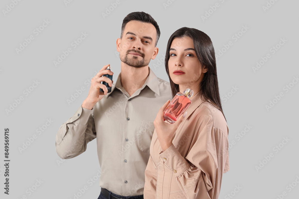 Young couple with bottles of perfume on light background