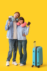 Wall Mural - Couple of young tourists with passports and suitcase on yellow background