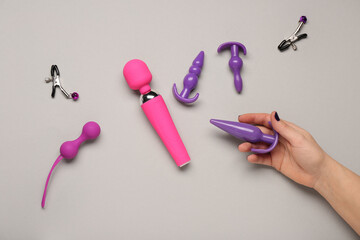 Wall Mural - Female hand with different sex toys on light background