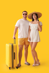 Sticker - Beautiful young happy couple of tourists with suitcase on yellow background