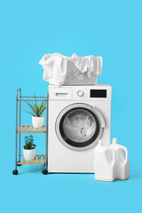 Wall Mural - Modern washing machine with detergents and basket full of dirty clothes on blue background