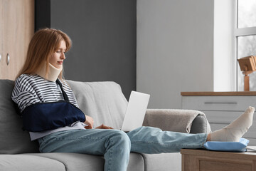 Canvas Print - Injured young woman after accident using laptop on sofa at home