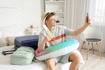 Poster - Male tourist with passport and swim ring taking selfie in hotel room