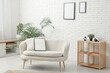 © Pixel-Shot - Modern living room with houseplant and blank picture frame on sofa and white brick wall
