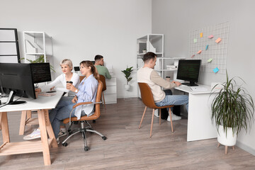 Wall Mural - Team of programmers working at tables in office