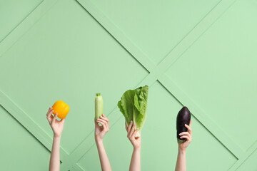 Wall Mural - Female hands holding fresh vegetables on green background