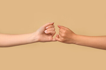 Women making pinky promise on color background, closeup. Friendship Day celebration